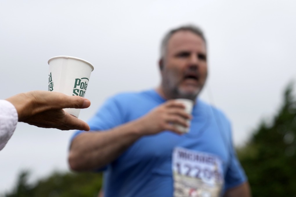 A volunteer holds out a cup of water for runners in the Falmouth Road Race in the US state of Massachusetts. Heatstroke among runners is becoming more of a risk as climate change increases the number of hot days. Photo: AP