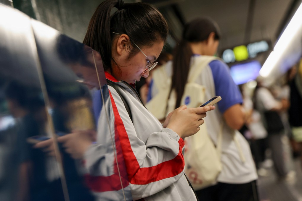 Young people use mobile phones while waiting for a train in Hong Kong. Australia’s minimum age limit for social media use could be as high as 16. Photo: Jelly Tse