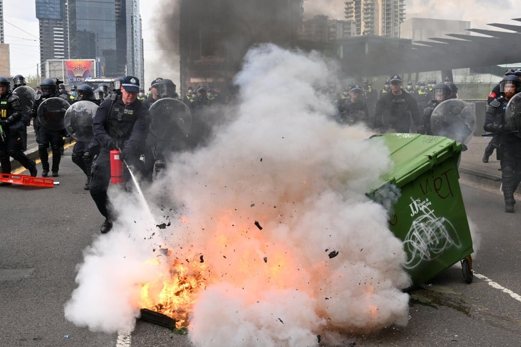 Police attempt to extinguish a fire set by protesters during a rally against the LandForces International Land Defence Exposition in Melbourne on Wednesday. Photo: EPA-EFE