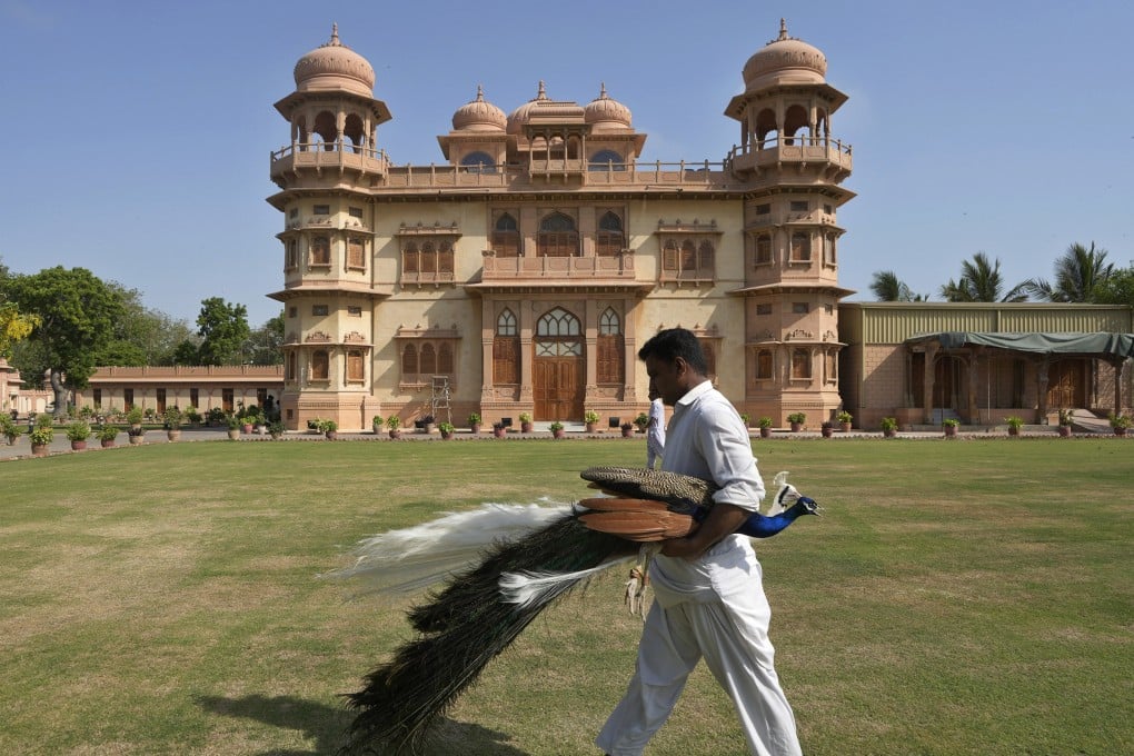A worker moves a peacock from the lawn of Mohatta Palace in Karachi, which was built in the 1920s and has since been turned into a museum. Photo: AP