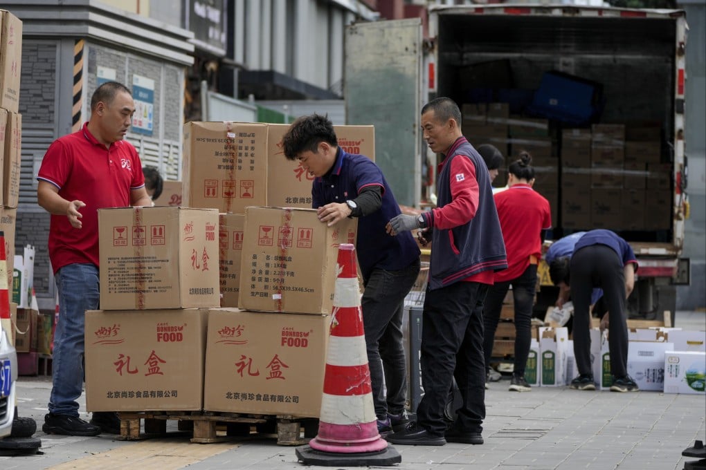 Workers load and pack gift boxes outside a supermarket in Beijing. Photo: AP