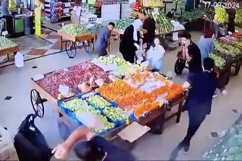 A man falls to the floor (left) after an explosion at an indoor vegetable market in Beirut on Tuesday. Photo: AFP