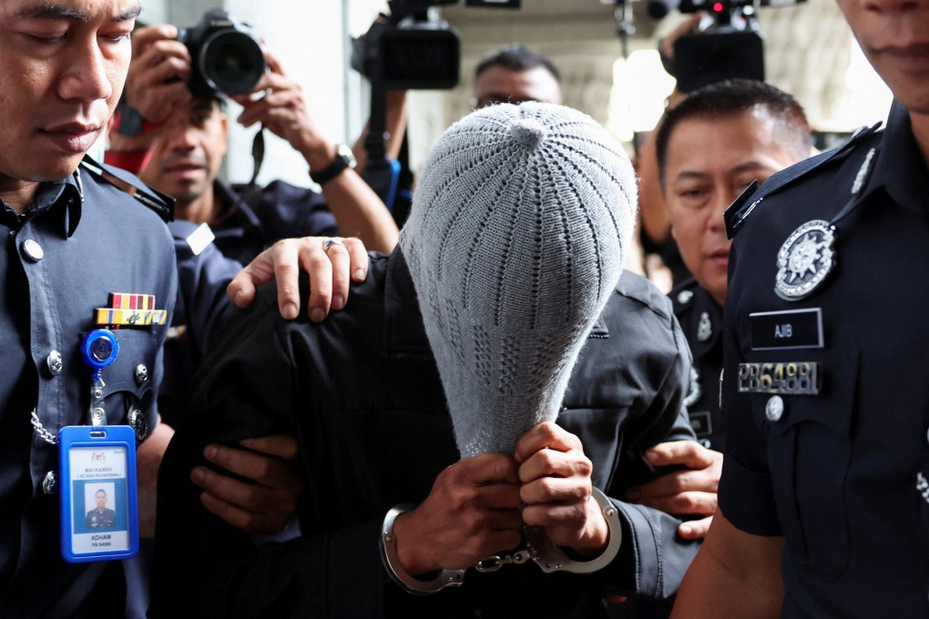 A member of Global Ikhwan Service and Business Holdings (GISB) covers his face as he is escorted by police officers after being charged at a court in Putrajaya, Malaysia on September 18. Photo: Reuters