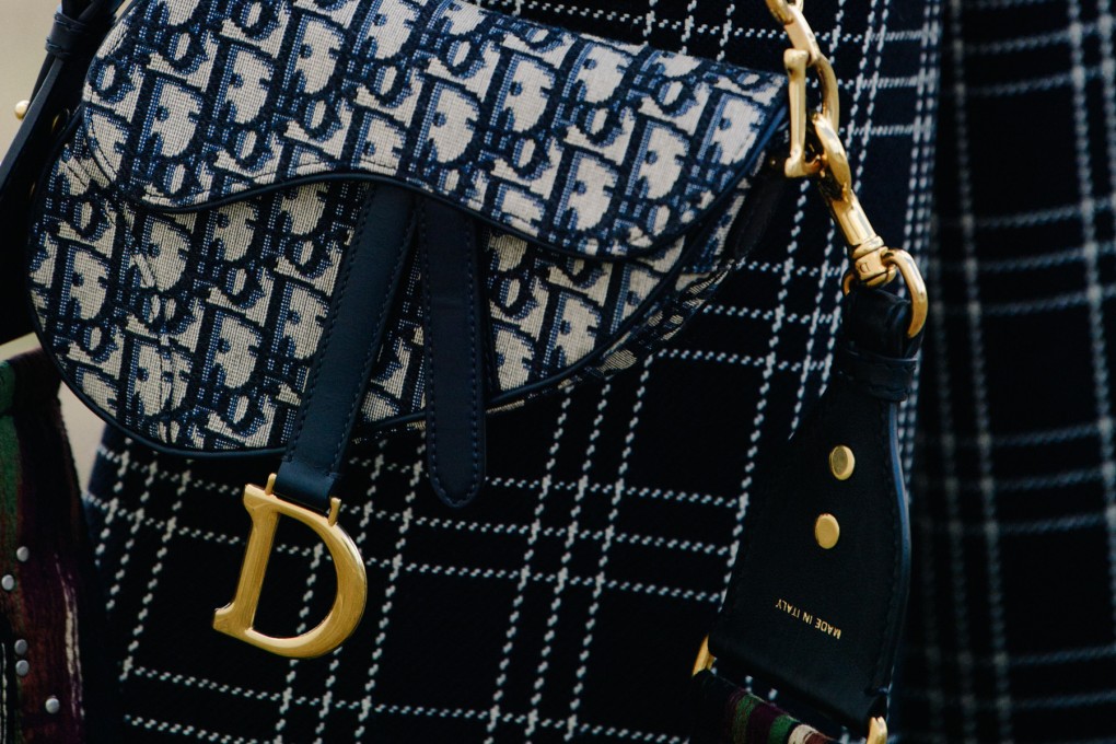 A guest carries a Dior Saddle bag at the Dior spring/summer 2019 show in Paris, France. The LVMH-owned label is under the spotlight, together with other luxury brands including Giorgio Armani and Alviero Martini, over the working conditions of migrant workers in their Italian workshops.