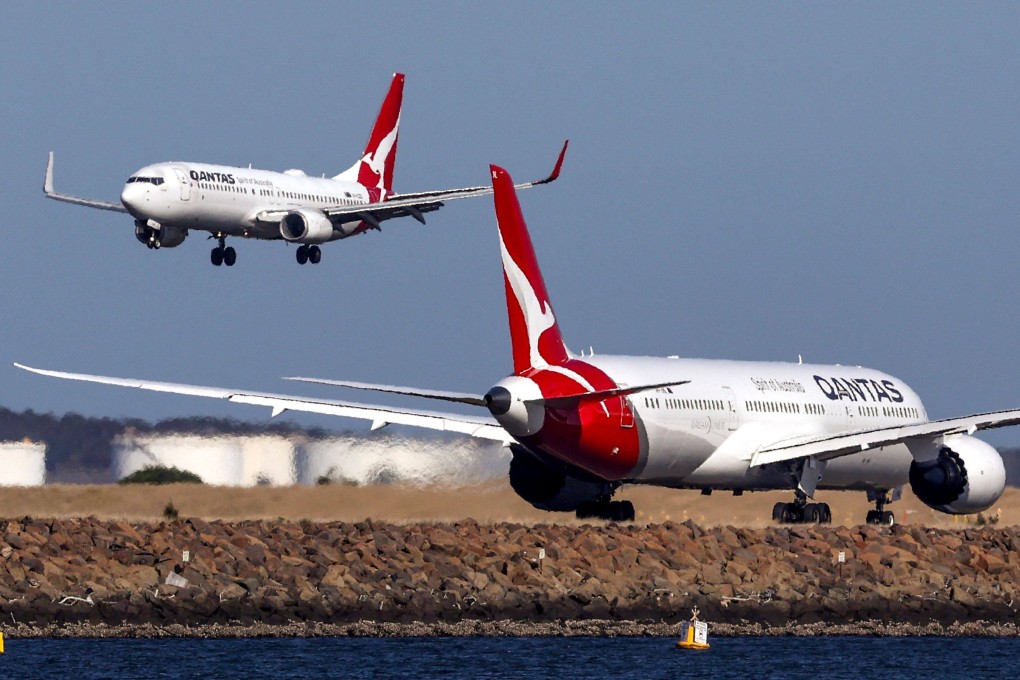 A Qantas Airways plane comes in to land next to another Qantas aircraft preparing to take-off at Sydney International Airport. Photo: AFP