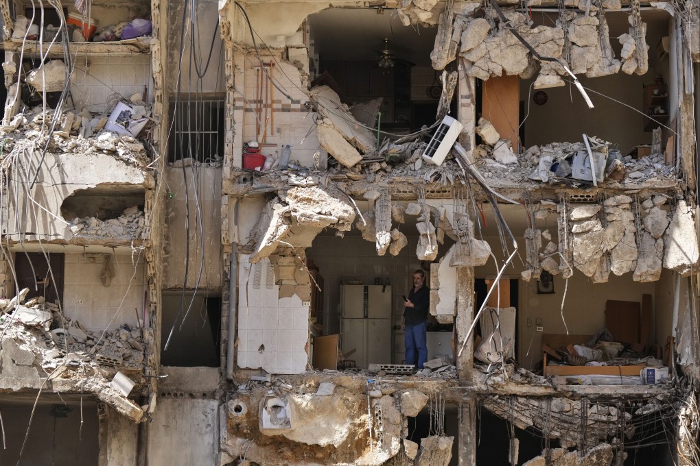 A man watches rescuers sift through rubble after an Israeli strike in Beirut’s southern suburbs. Photo: AP