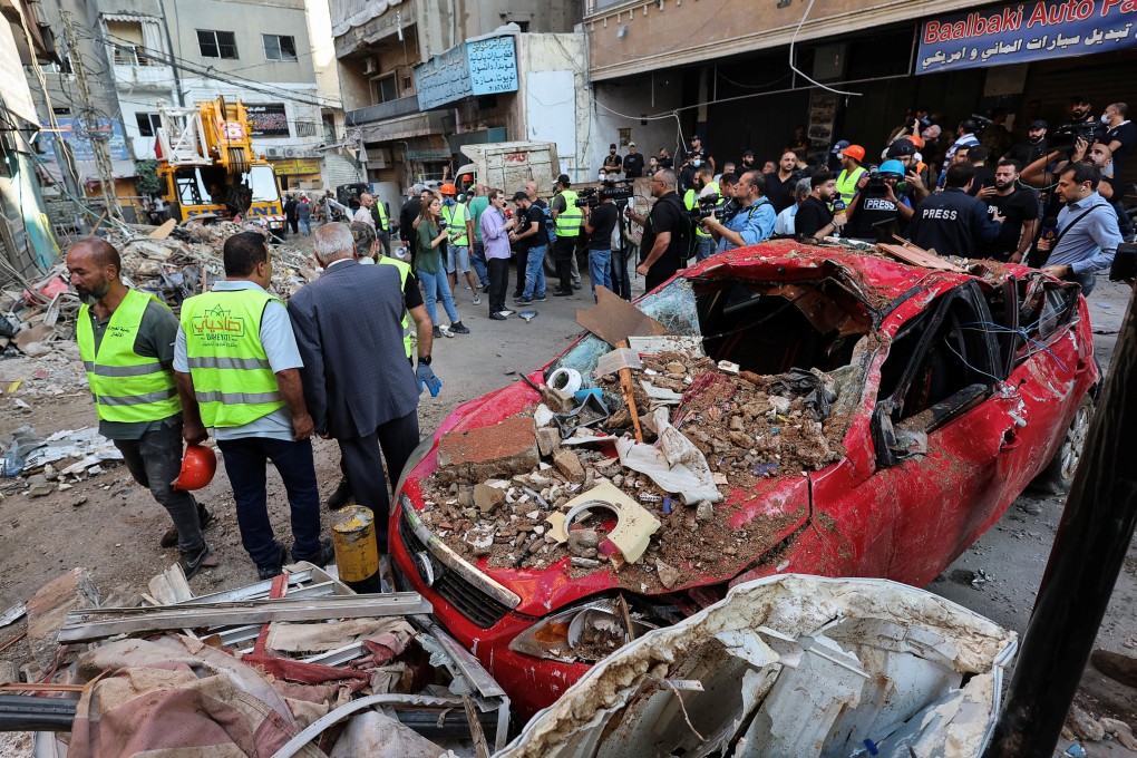 People stand next to a destroyed car, at the site of an Israeli strike in Beirut, Lebanon on September 24. Photo: Reuters