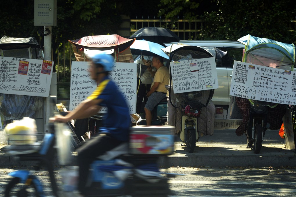 A motorist passes by placards showing properties for lease on electric scooters parked along the sidewalk in Hangzhou in east China’s Zhejiang province in August 2024. Photo: AP