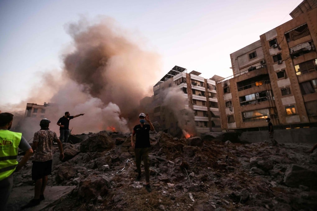 People stand amid the rubble of a building in Beirut, Lebanon’s capital, destroyed in an Israeli air strike on September 27. Photo: AFP