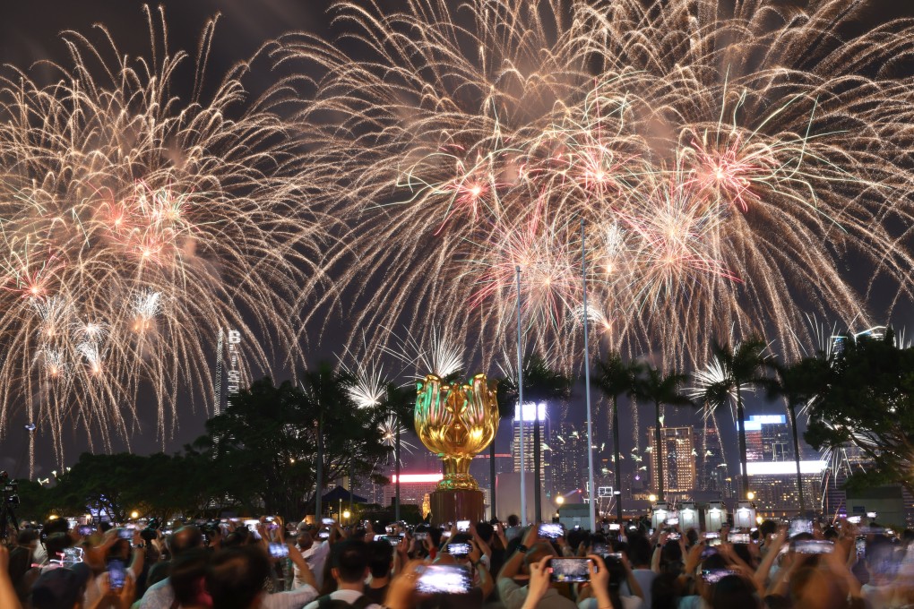 People take photographs of a firework display over Victoria Harbour to celebrate National Day at Golden Bauhinia Square in Wan Chai on October 1. Photo: Dickson Lee