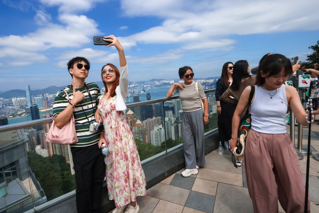 Visitors pose for photos against the backdrop of Hong Kong’s iconic skyline. Photo: Jonathan Wong