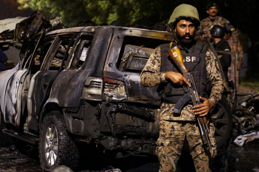 A Pakistan Airport Security Force member stands guard near the wreckage of vehicles after an explosion near Jinnah International Airport in Karachi on October 6, 2024. Photo: Reuters