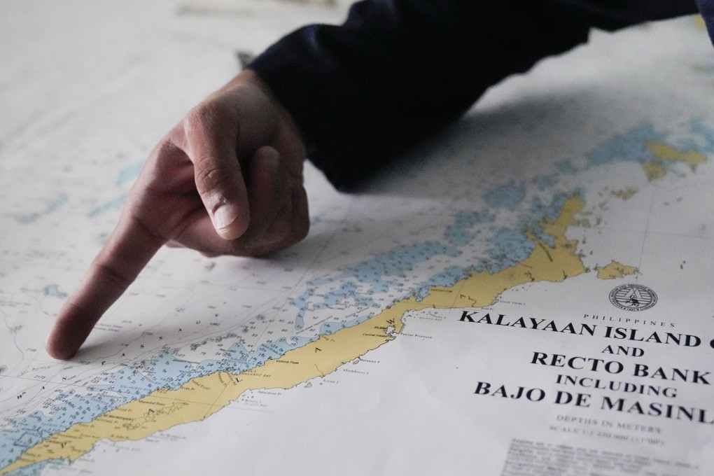 A member of the Philippine coastguard points at a map showing Palawan province and other Philippine-occupied areas in the South China Sea last year. Photo: AP