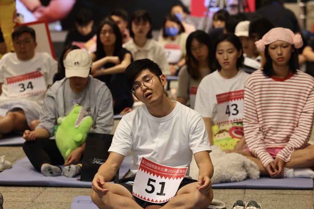 Education psychologist Denis Kwan (centre) takes part in the International Space-Out Competition 2024 in Hong Kong, at PMQ in Central, with more than 70 other participants. The event invites people to sit and do nothing for 90 minutes, highlighting how this can benefit mental health and lower stress. Photo: Dickson Lee