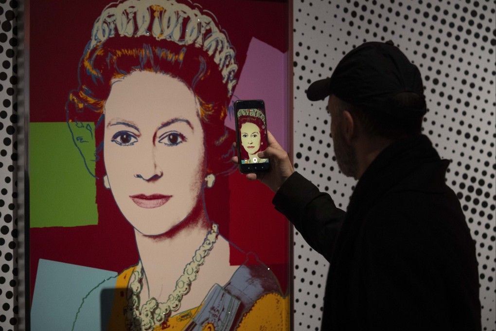 A man takes a photo of Andy Warhol’s artwork depicting Queen Elizabeth, at a preview of the artist’s Reigning Queens exhibition in Apeldoorn, the Netherlands. Photo: AP