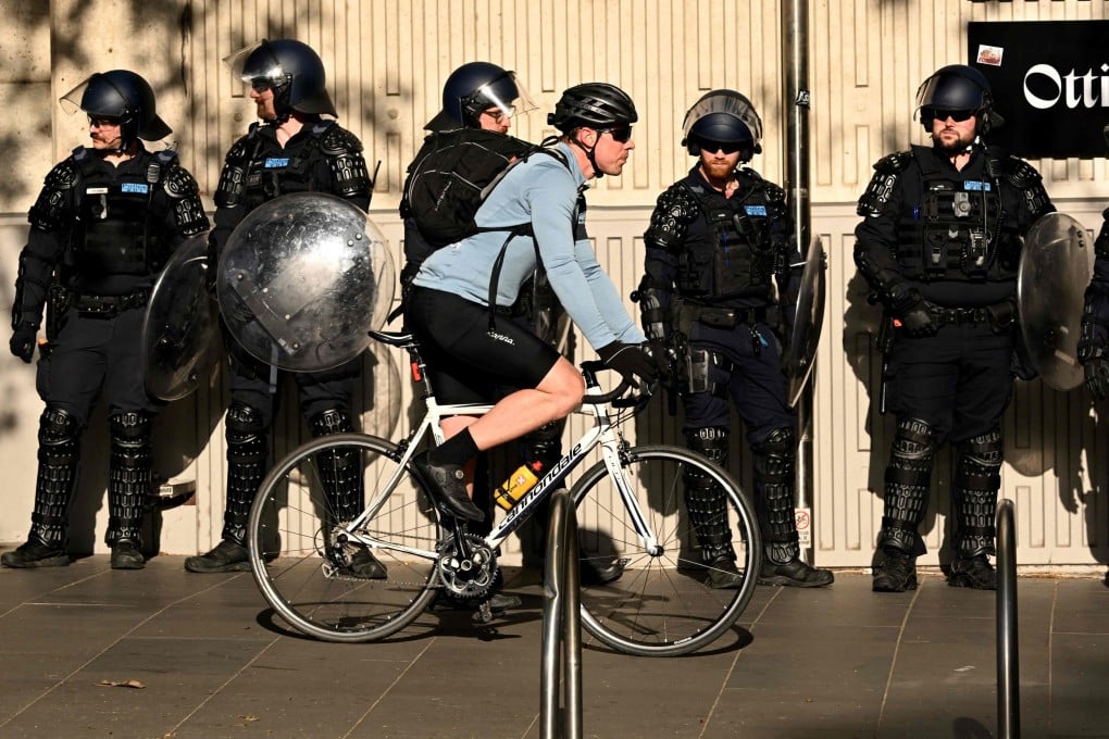 File Photo: A cyclist passes riot police outside the Land Forces 2024 arms fair in Melbourne on September 12. Photo: AFP