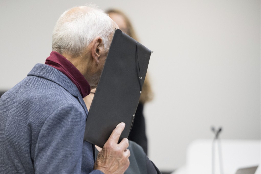 Defendant Martin Manfred Naumann, 80, stands in court on Monday and covers his face before the verdict is announced in his trial for the 1974 murder of a Polish citizen at the former Berlin-Friedrichstrasse border crossing. Photo: via AP