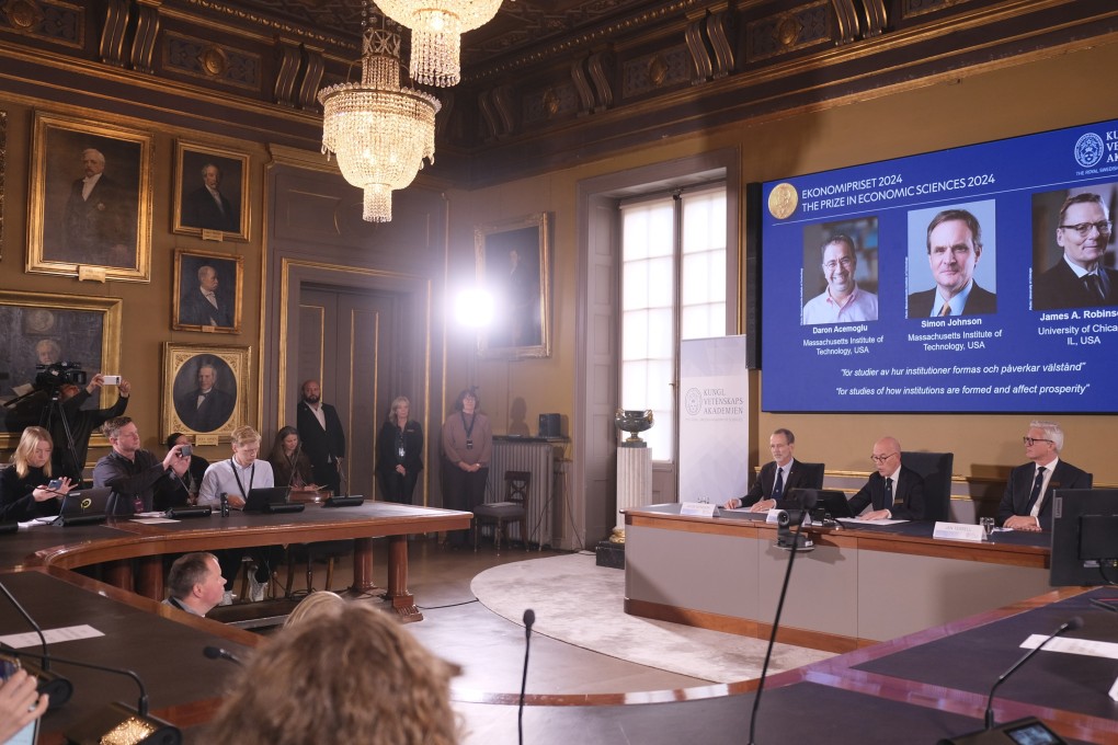 Members of the Nobel assembly announce the 2024 prize in economics, awarded to Daron Acemoglu, Simon Johnson and James A Robinson, seen on screen, during a press conference in Stockholm on Monday. Photo: Xinhau