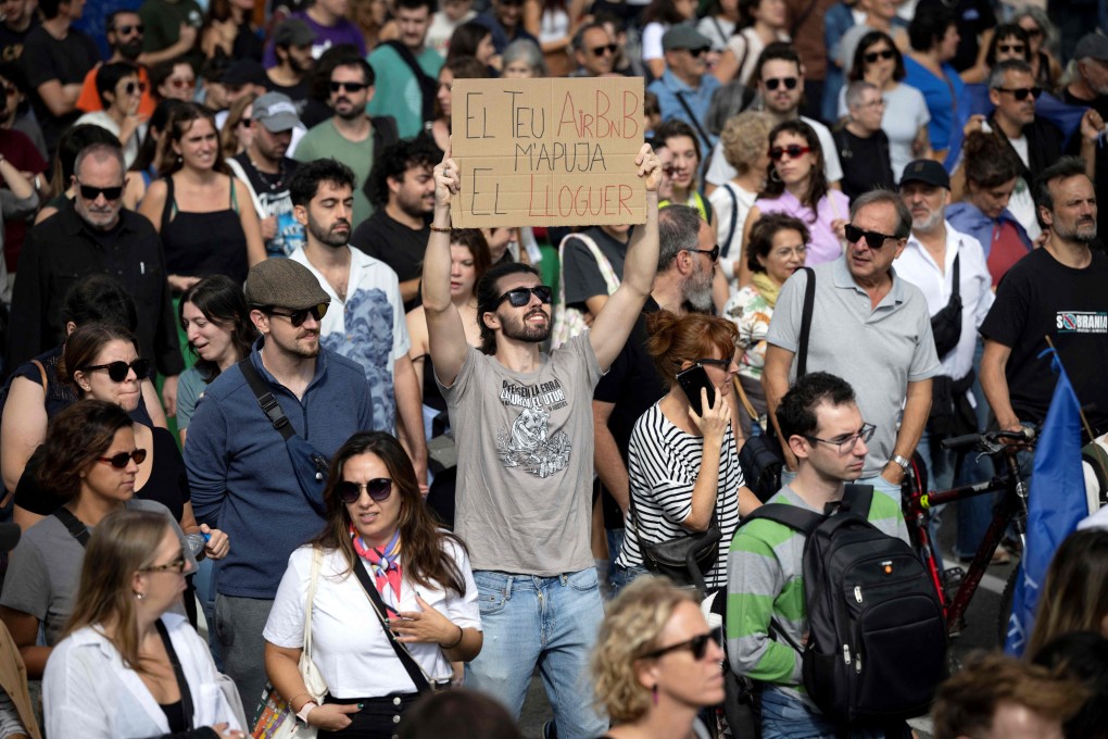 A protester holds a banner reading “Your AirBnB increases my rent” during a demonstration in Barcelona on October 13, 2024. Similar protests have taken place across Spain recently, while elsewhere in Europe, the negative effects of mass tourism are being dealt with in other ways. Photo: AFP