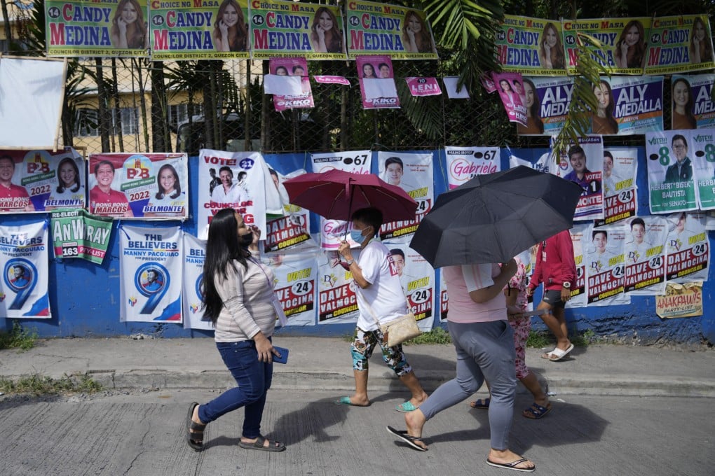 Voters pass by campaign posters outside a polling centre in Quezon City in 2022. More than 66 million registered Filipinos will cast their votes for over 18,280 candidates vying for posts across the country during midterm elections next May. Photo: AP
