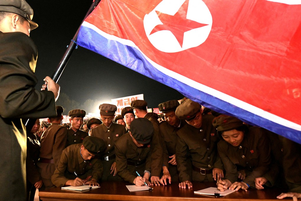 Young people, including students and youth league officials, sign petitions to join or return to the army at an undisclosed location in North Korea. Photo: KCNA via Reuters