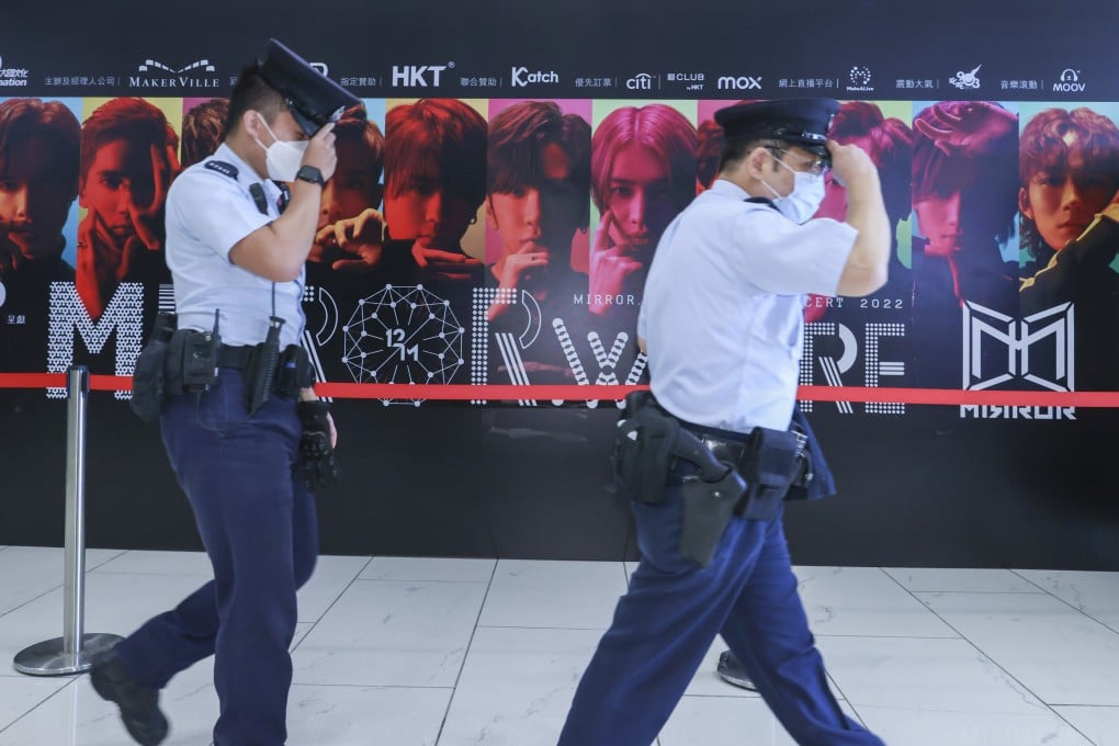 Security officers walk past a display promoting Cantopop boy band Mirror. Photo: Dickson Lee