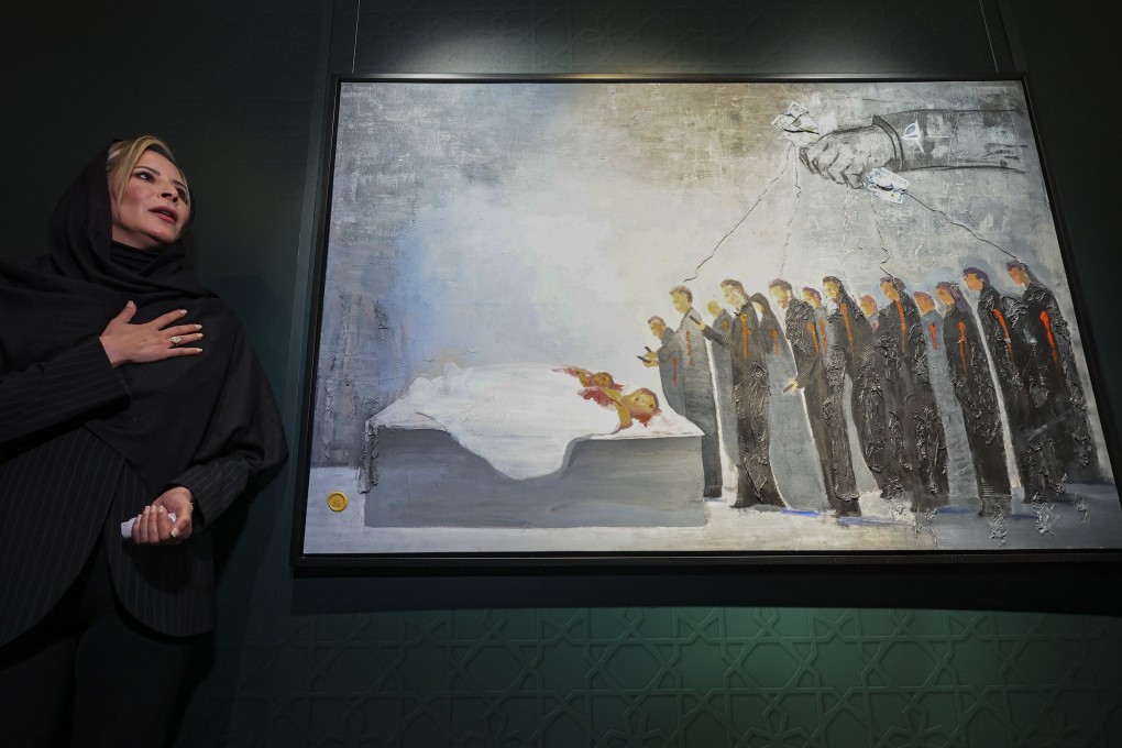 Aisha Gaddafi, daughter of slain Libyan leader Muammar Gaddafi, presents one of her paintings showing a crowd hovering over the corpses of her father and her brother at the State Museum of Oriental Art in Moscow, which is mounting a show of her art. Photo: EPA-EFE