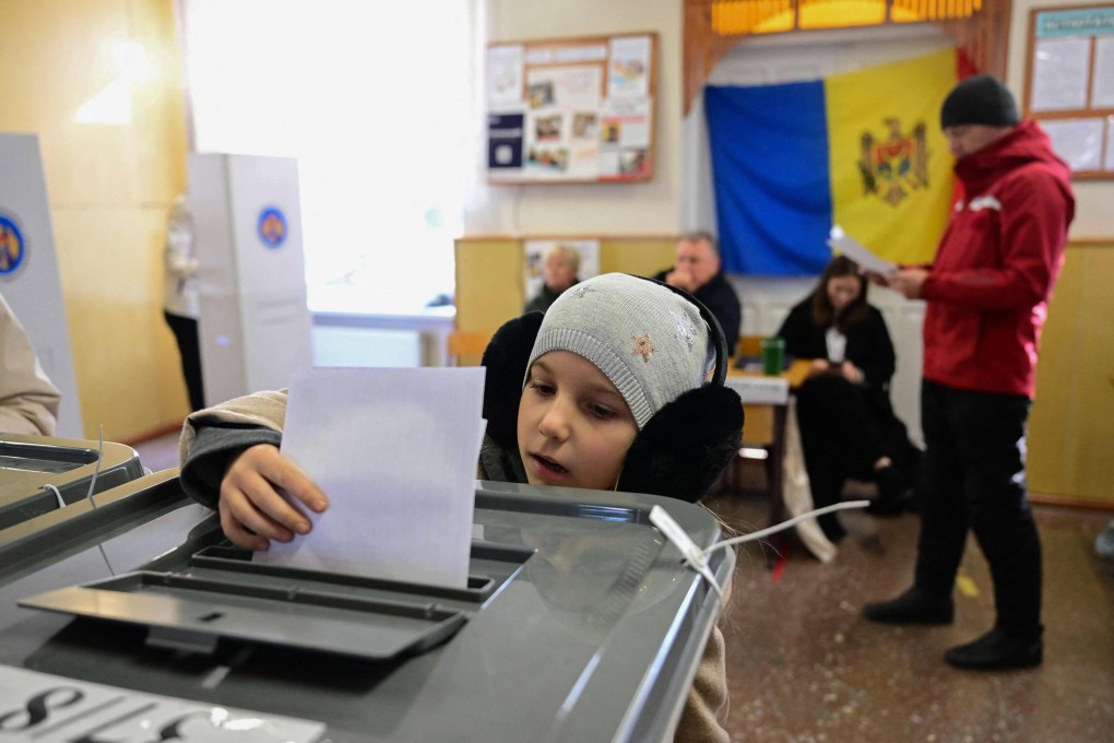 A Moldovan child casts the ballot of a relative on Sunday during the presidential election and referendum on joining the European Union. Photo: AFP