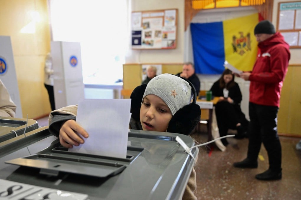 A Moldovan child casts the ballot of a relative on Sunday during the presidential election and referendum on joining the European Union. Photo: AFP