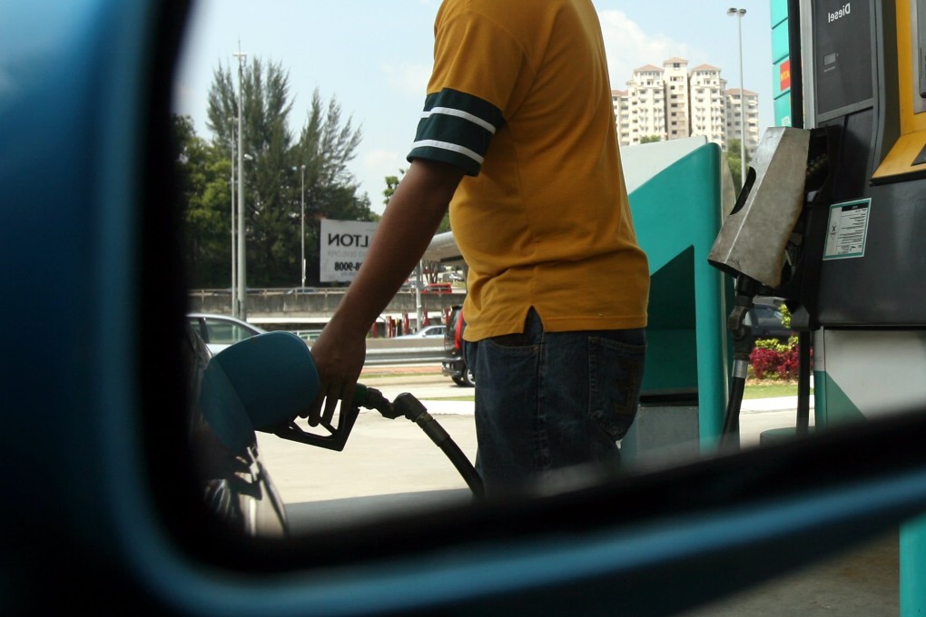 A man fills the tank of a car at a petrol station in Kuala Lumpur. Photo: AFP