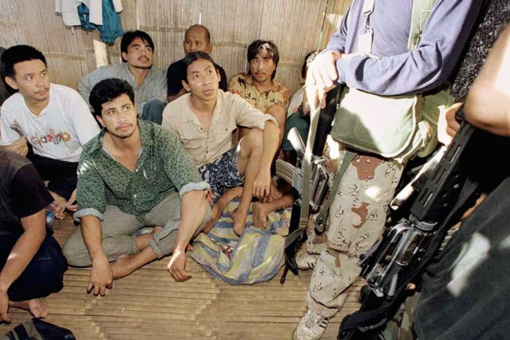 Malaysian hostages are seen being guarded by armed militants at a shack on Jolo Island, southern Philippines, in May 2000. Photo: Reuters