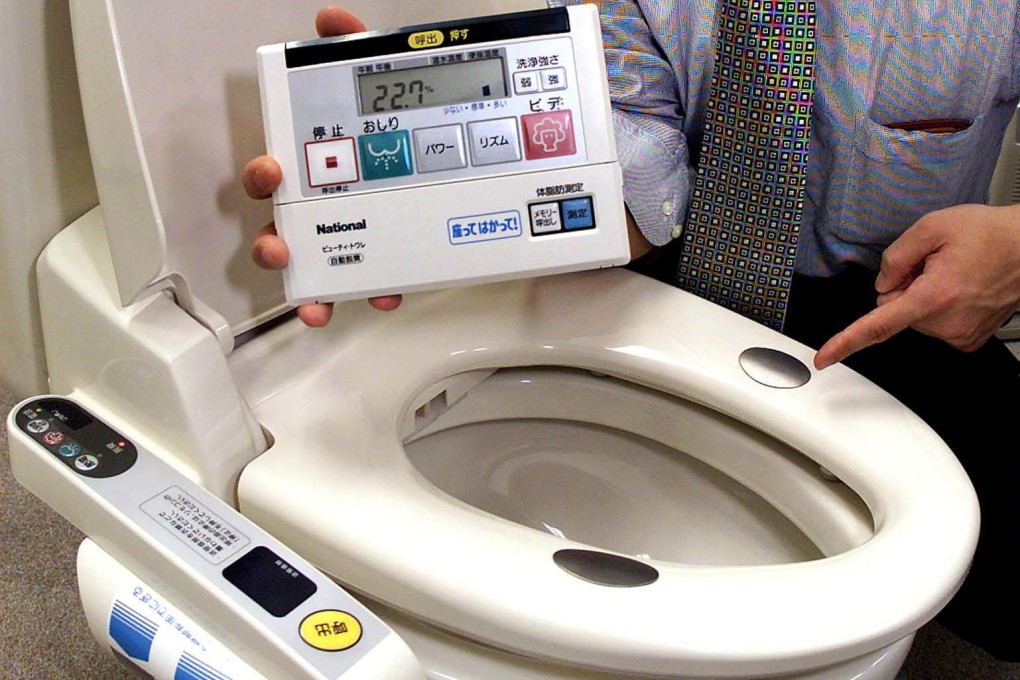 An employee of Japanese electronics giant Matsushita displaying the company’s latest hi-tech toilet seat model in 2002. Photo: AFP