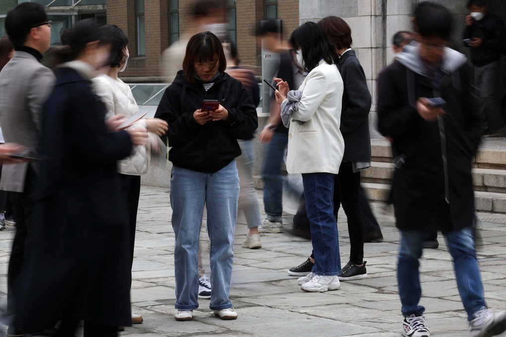 People look at their mobile phones to check the mobile financial app Toss as they gather at Seoul Museum of Art in Seoul on April 13, 2023. Online financial service providers such as Toss have made significant inroads into payments, lending and other areas once dominated by banks. Photo: Reuters