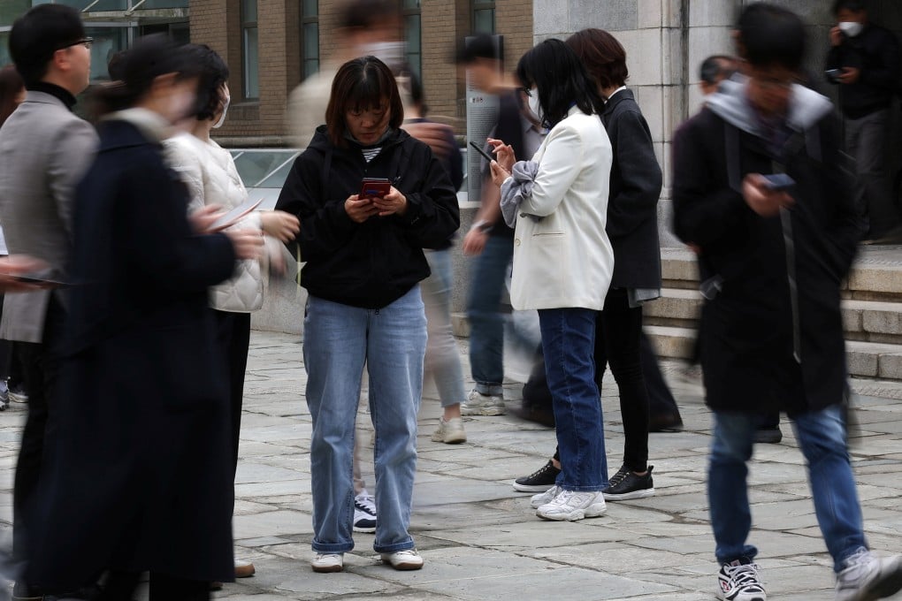 People look at their mobile phones to check the mobile financial app Toss as they gather at Seoul Museum of Art in Seoul on April 13, 2023. Online financial service providers such as Toss have made significant inroads into payments, lending and other areas once dominated by banks. Photo: Reuters