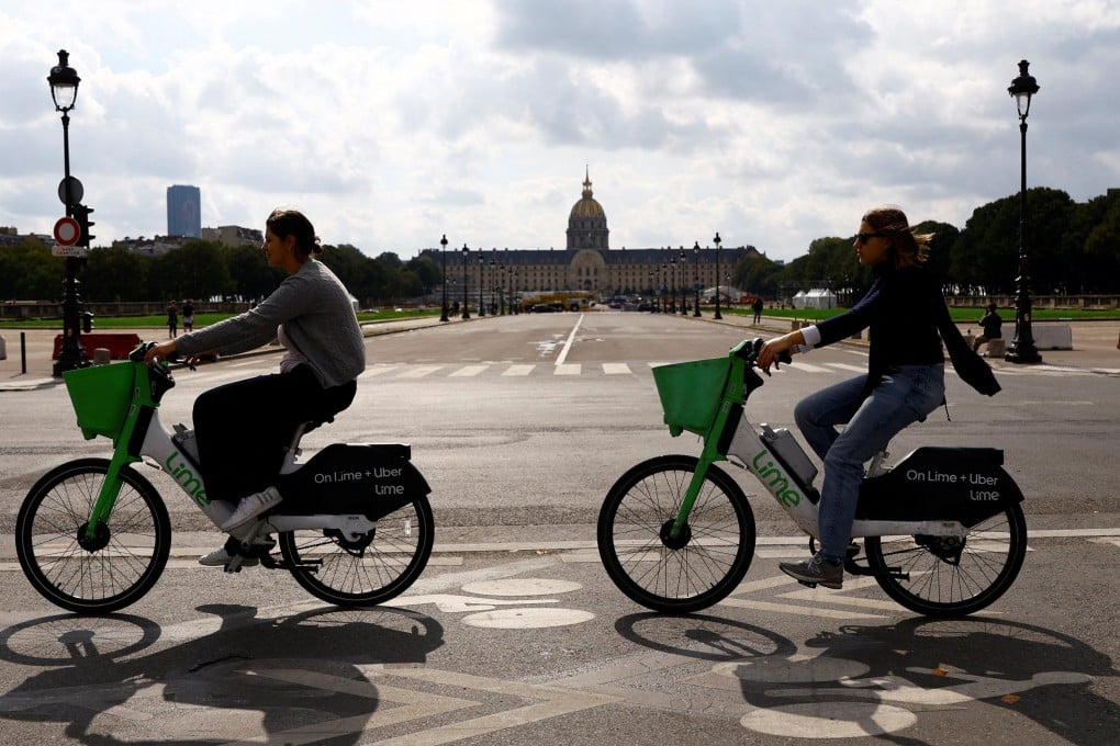 Women ride electric Lime bicycles on a bike path past the Hotel des Invalides in Paris, France. Photo: Reuters
