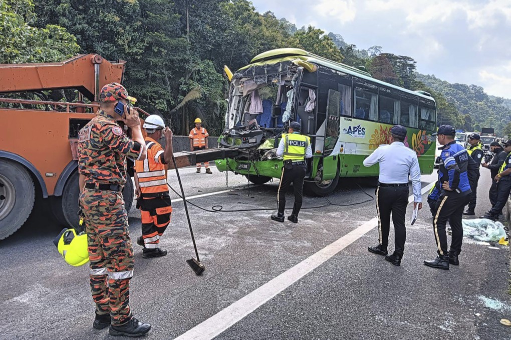 Officers inspect the tour bus that smashed into the rear of a truck in Taiping, Malaysia’s Perak state, on Thursday. Photo: Malaysian Fire and Rescue Department via AP