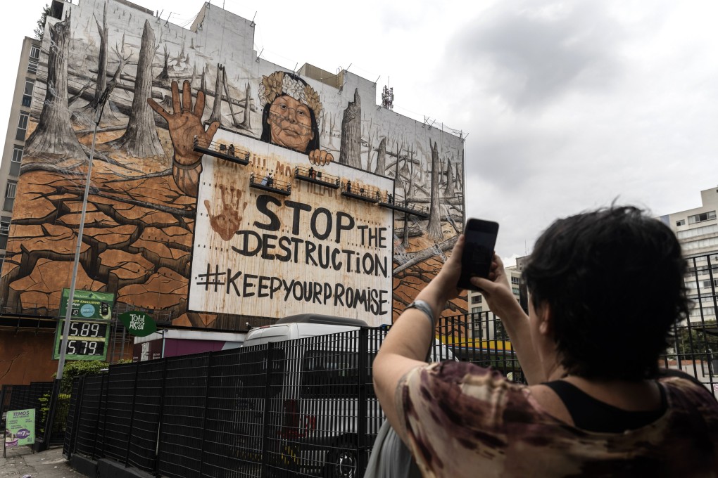 A passerby takes a photo of a mural painted with ashes from the fires ravaging Brazil in Sao Paulo on October 23. The huge mural by Brazilian artist Mundano demands that agricultural companies stop deforestation in the Amazon. Photo: EPA-EFE
