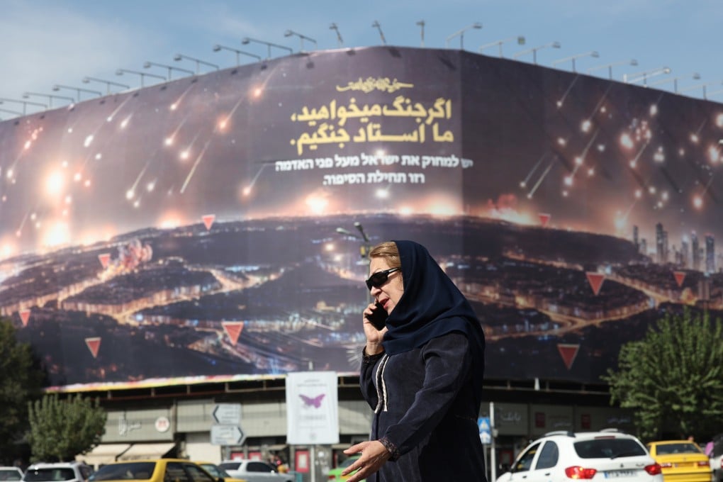 A woman walks past an anti-Israel hoarding in Tehran on October 26 depicting Iran’s recent missile attack on Israel and a sentence reading in Persian: “If you want war, we are the master of war.” Photo: EPA-EFE