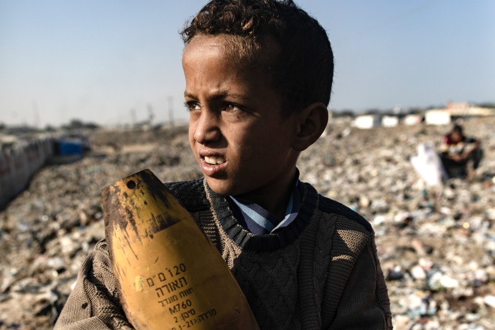 A Palestinian boy holds an Israeli artillery shell, found while sorting through rubbish amid a shortage of cooking gas and fuel, at the Khan Younis refugee camp in the southern Gaza Strip on Monday. Photo: EPA-EFE