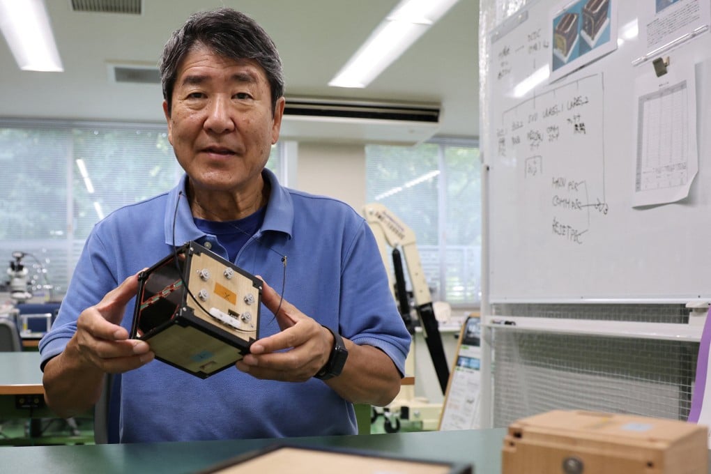 Takao Doi, a former Japanese astronaut and professor at Kyoto University in Japan, holds an engineering model of LignoSat at his laboratory last month. Photo: Reuters