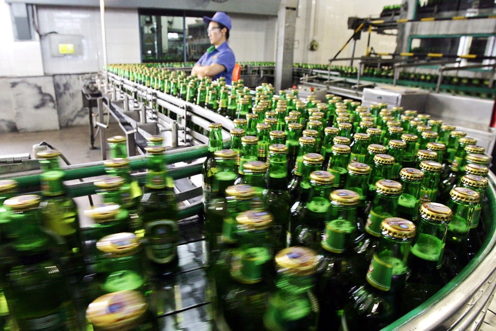A worker inspects the bottles of Tsingtao beer rolling out from one of the four breweries in the eastern Chinese port city of Qingdao. Photo: AFP