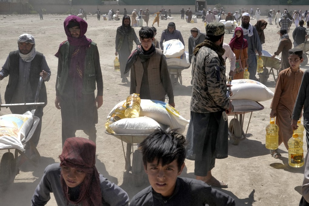 A Taliban fighter stands guard as people receive food rations distributed by a Chinese humanitarian aid group, in Kabul, Afghanistan, on April 30, 2022. Afghanistan also had the highest number of children made homeless by climate disasters of any country as of the end of 2023, according to an August report from international aid agency Save the Children. Photo: AP