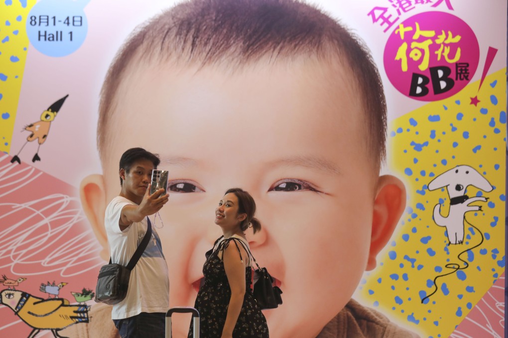 A couple takes a selfie in front of a poster featuring a baby, during an exhibition of children’s products at the Hong Kong Convention and Exhibition Centre in Wan Chai on August 2. Photo: Xiaomei Chen