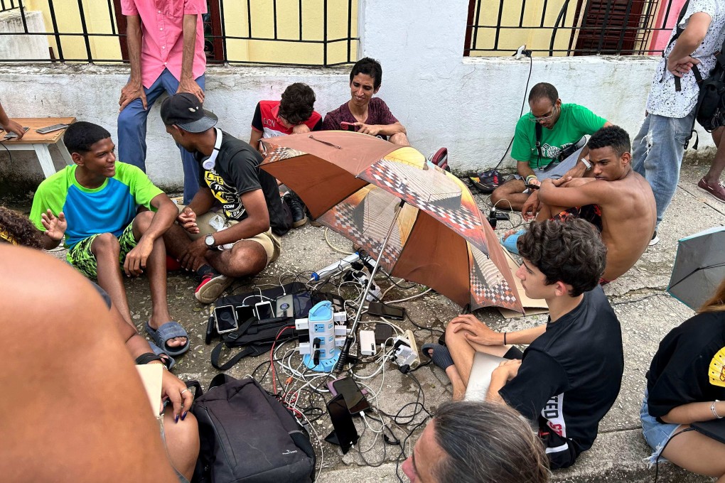 People charge their mobile phones in the aftermath of Hurricane Rafael last week. Photo: AFP