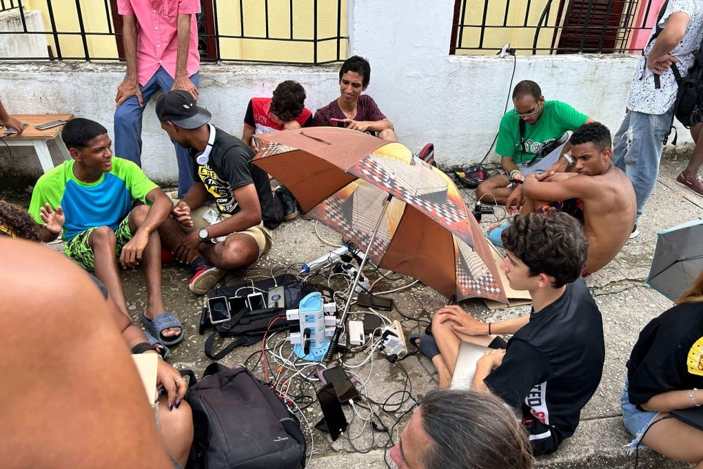 People charge their mobile phones in the aftermath of Hurricane Rafael last week. Photo: AFP