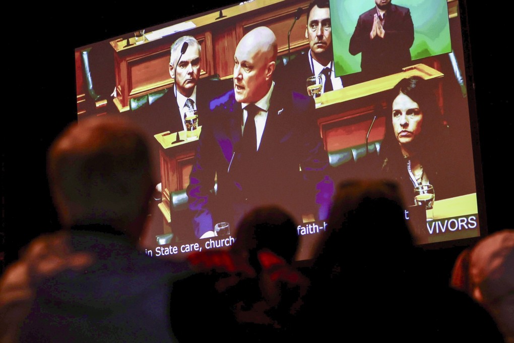 New Zealand’s Prime Minister Christopher Luxon is shown on a screen on Tuesday as he makes a “formal and unreserved” apology in parliament for the widespread abuse, torture and neglect of hundreds of thousands of children and vulnerable adults in care. Photo: Stuff via AP