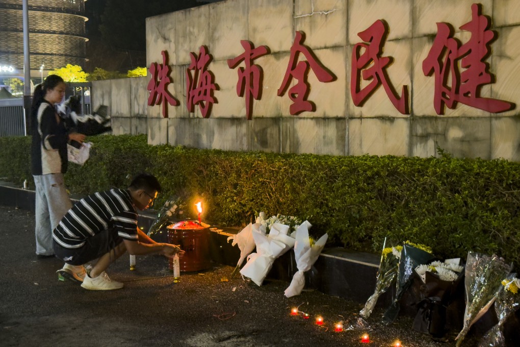 A man lights a candle near flowers placed outside a Zhuhai sports centre on Tuesday where a car driver deliberately rammed into people exercising a day earlier. Photo: AP