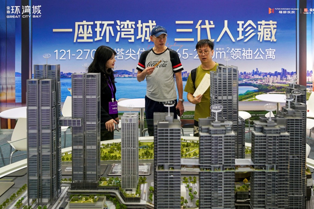 An agent speaks with potential buyers near a scale model of residential buildings at a property fair in Shenzhen, Guangdong province, on Tuesday. Photo: Reuters