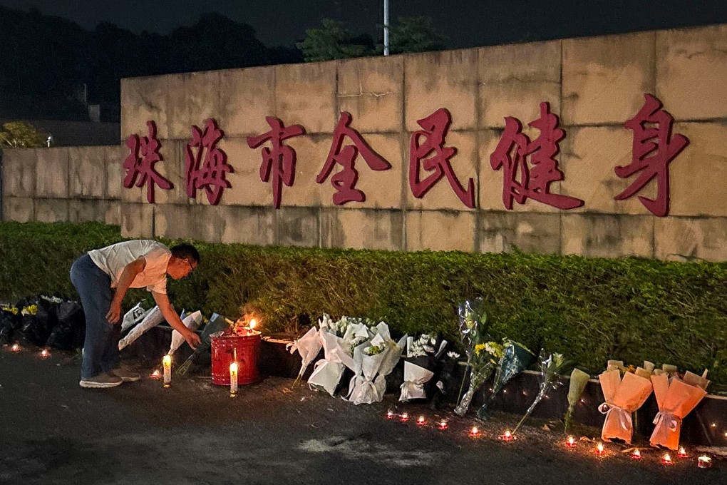 A man looks at candles left outside the Zhuhai Sports Centre, a day after a car drove into a crowd of people exercising there, killing at least 35. Photo: Amber Wang