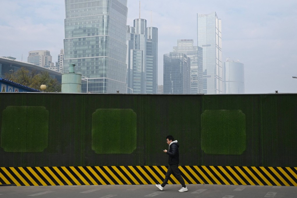 A man walks past the wall of a construction site in the central business district in Beijing. Photo: AFP